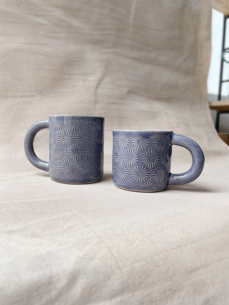 taza de cerámica hecha a mano con esmalte morado brillante y relieve de margaritas.