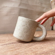 Cargar imagen en el visor de la galería, taza de cerámica hecha a mano con esmalte biege neutro y relieve de margaritas.
