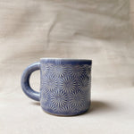 taza de cerámica hecha a mano con esmalte morado brillante y relieve de margaritas.
