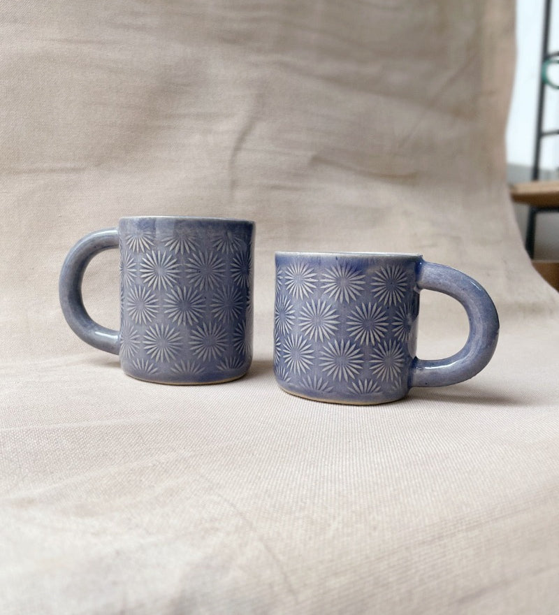taza de cerámica hecha a mano con esmalte morado brillante y relieve de margaritas.