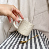 taza de cerámica hecha a mano con esmalte beige neutro y relieve de margaritas.