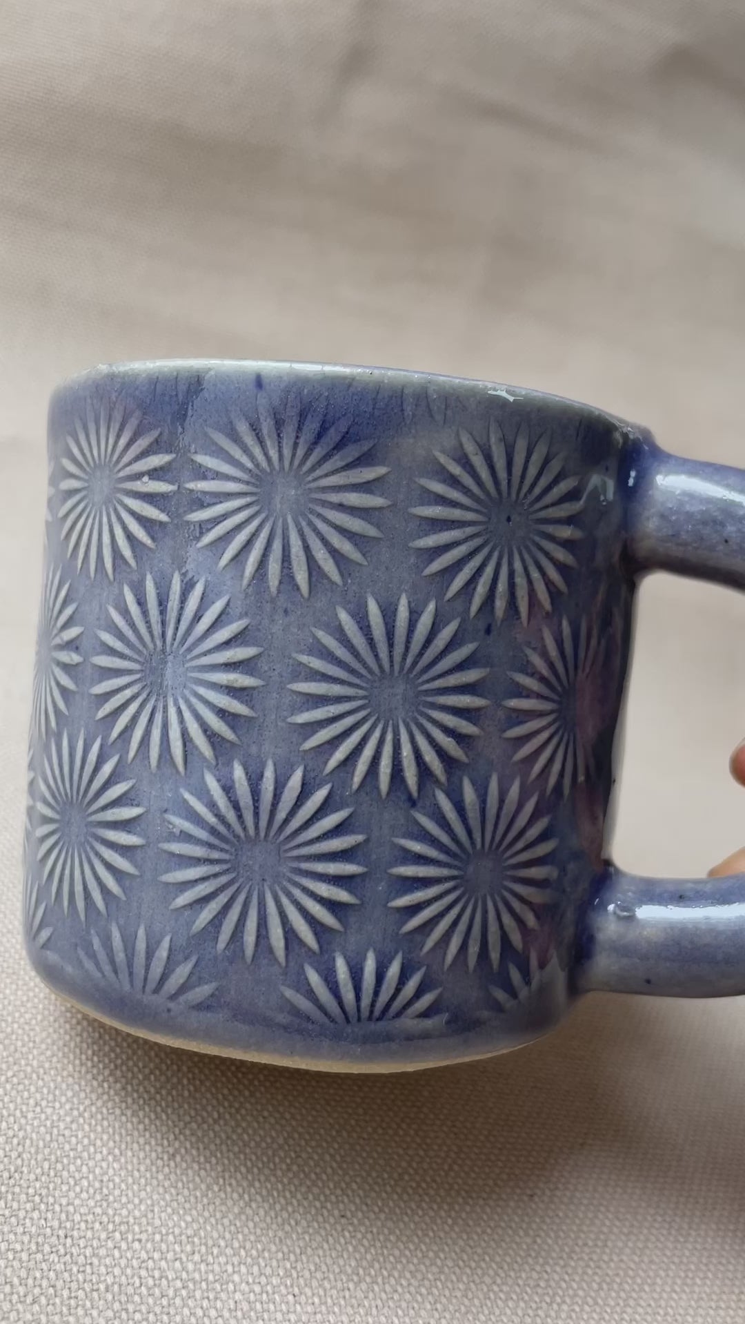 taza de cerámica hecha a mano con esmalte morado brillante y relieve de margaritas.