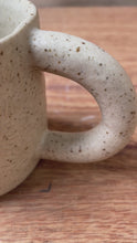 Cargar y reproducir el video en el visor de la galería, taza de cerámica hecha a mano con esmalte beige neutro y relieve de margaritas.
